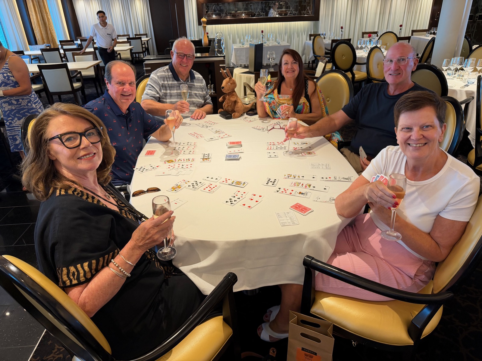 Left to right: Angela, Russ, Ian, Linda, Mark, and Karyn playing Hand and Foot around a cruise-ship table